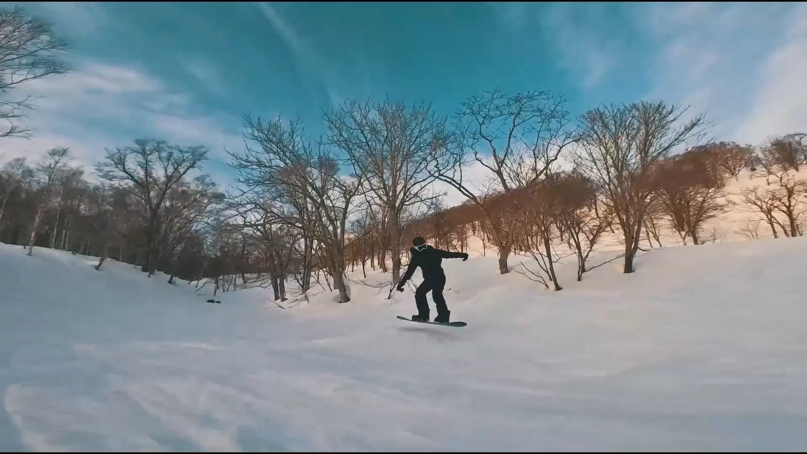 Sotravel 日本滑雪團中，一位單板滑雪者在藍天下的壓雪道上滑行